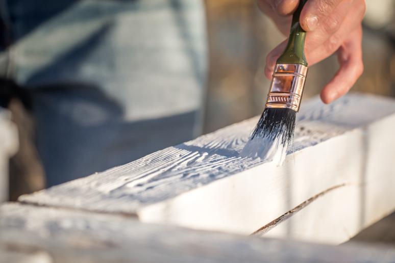 Hout schilderen met een kwast en witte verf